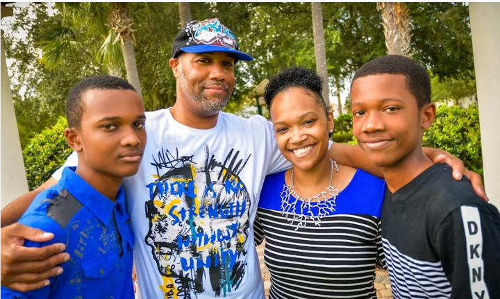 A family of four standing together outdoors.